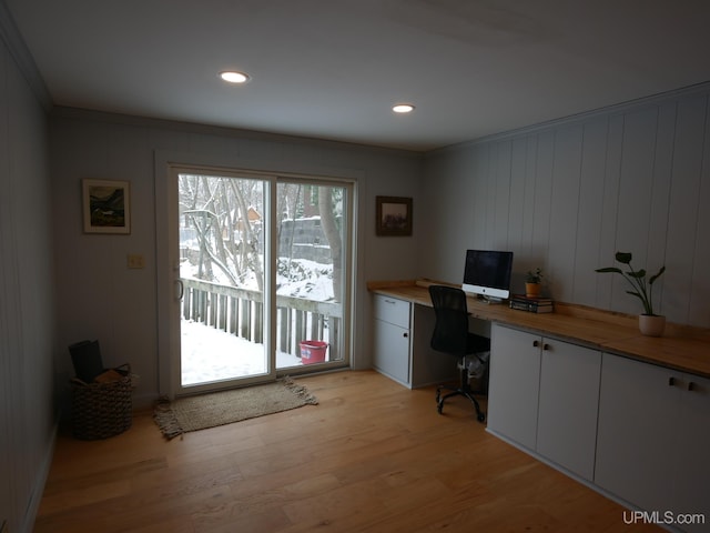 office area with light wood-type flooring, built in desk, and ornamental molding