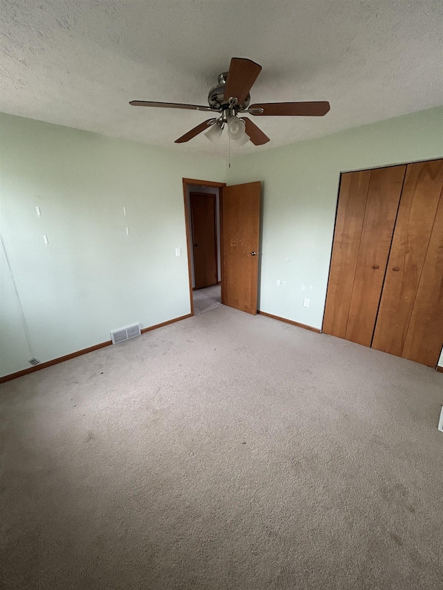 unfurnished bedroom with ceiling fan, light carpet, and a textured ceiling