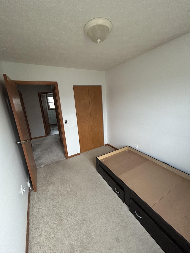 bedroom featuring a textured ceiling, light colored carpet, and a closet