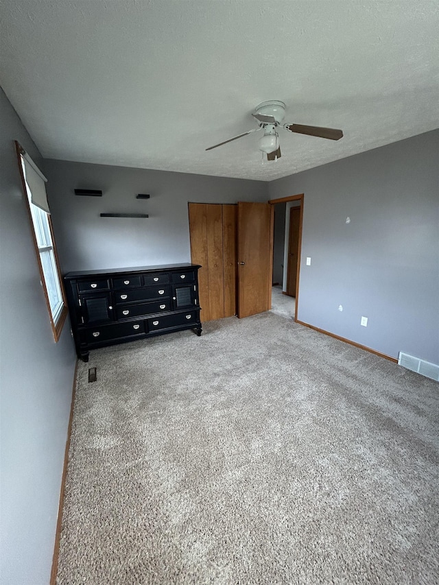 unfurnished bedroom featuring carpet, a textured ceiling, and ceiling fan