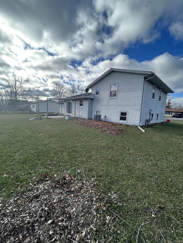 view of side of home featuring cooling unit and a yard