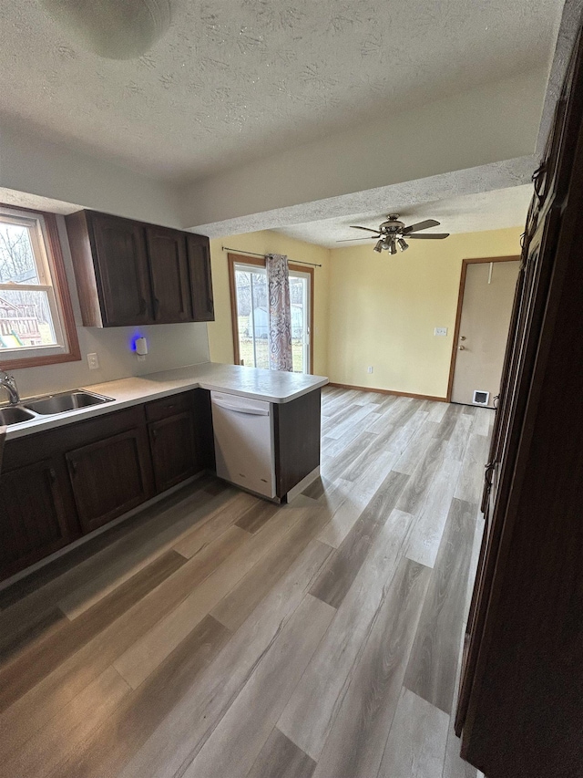 kitchen featuring dishwasher, sink, kitchen peninsula, light hardwood / wood-style floors, and a textured ceiling