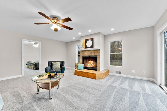 carpeted living room with a tile fireplace and ceiling fan