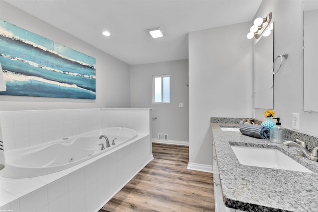 bathroom featuring vanity, wood-type flooring, and tiled tub