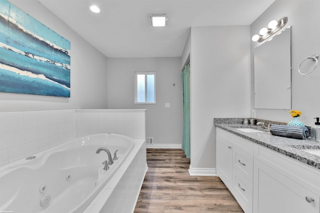 bathroom with vanity, wood-type flooring, and tiled tub