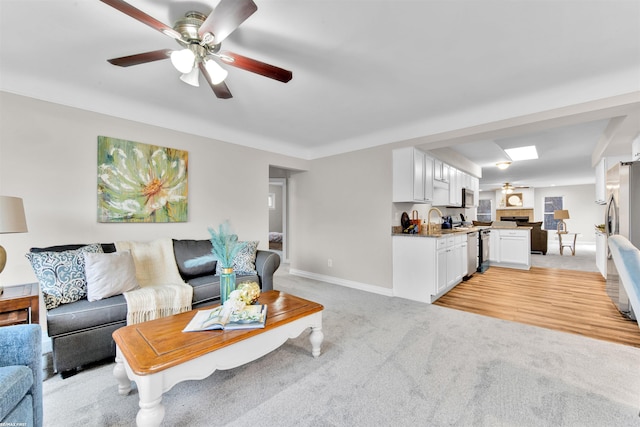 living room with light carpet, ceiling fan, and sink