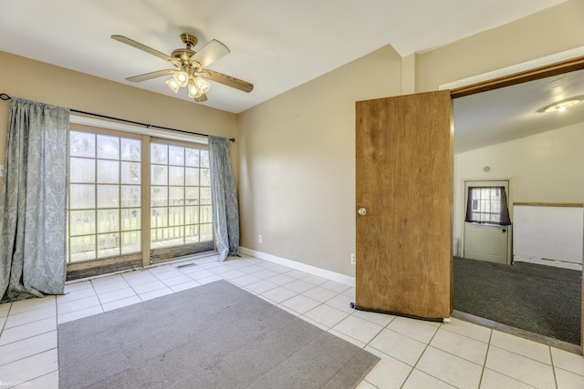 empty room with ceiling fan, light tile patterned floors, and vaulted ceiling