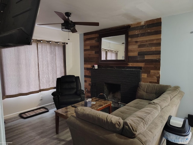 living room featuring hardwood / wood-style flooring, ceiling fan, a fireplace, and wooden walls