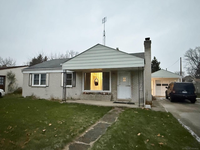 view of front of property with a garage, covered porch, an outbuilding, and a front yard