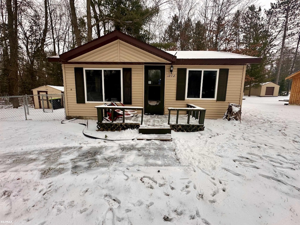 snow covered rear of property featuring an outdoor structure