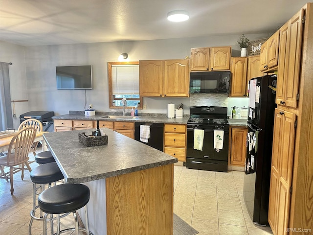 kitchen featuring sink, a center island, a breakfast bar area, light tile patterned floors, and black appliances