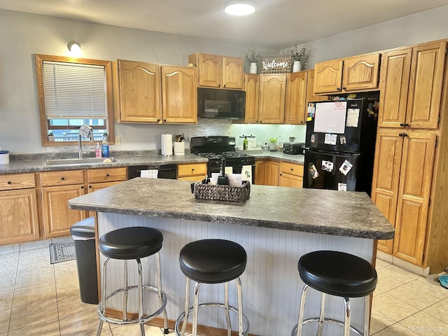 kitchen with sink, light tile patterned floors, a kitchen bar, a kitchen island, and black appliances