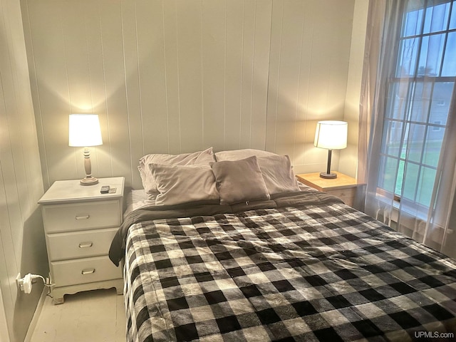 bedroom with multiple windows and wood walls