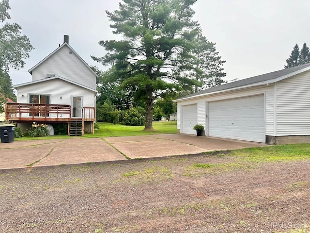 view of side of property featuring a deck, a garage, and a lawn