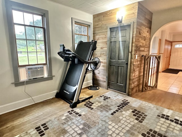 exercise room with wooden walls, cooling unit, and light hardwood / wood-style floors