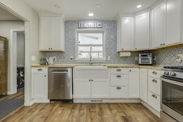 kitchen featuring appliances with stainless steel finishes, light wood-type flooring, and white cabinetry