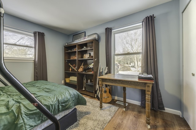 bedroom with multiple windows and dark hardwood / wood-style floors