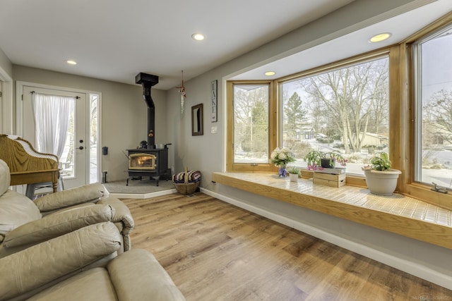 living room with plenty of natural light, a wood stove, and light hardwood / wood-style flooring