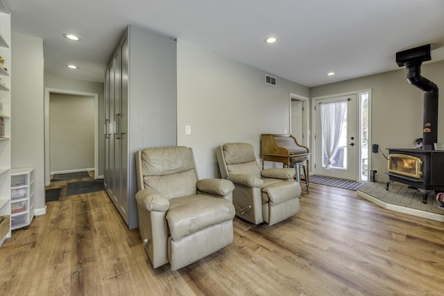 living area with a wood stove and light hardwood / wood-style floors