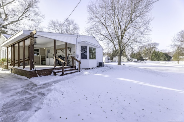 snow covered rear of property with covered porch