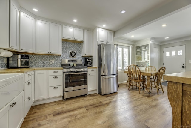 kitchen with backsplash, stainless steel appliances, white cabinetry, and light hardwood / wood-style floors