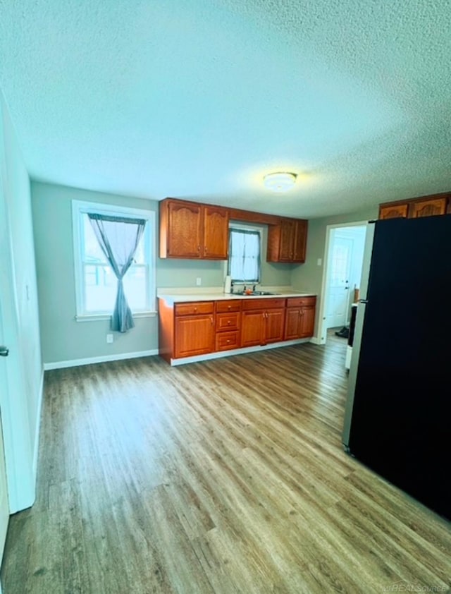 kitchen featuring sink, hardwood / wood-style floors, stainless steel refrigerator, and a textured ceiling