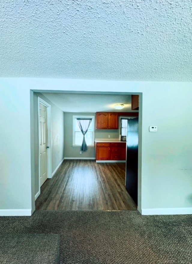 unfurnished living room with a textured ceiling and dark colored carpet