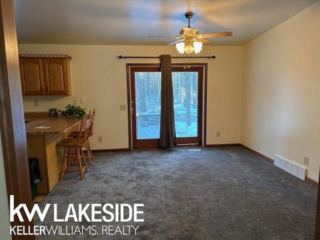 unfurnished dining area with ceiling fan and dark carpet