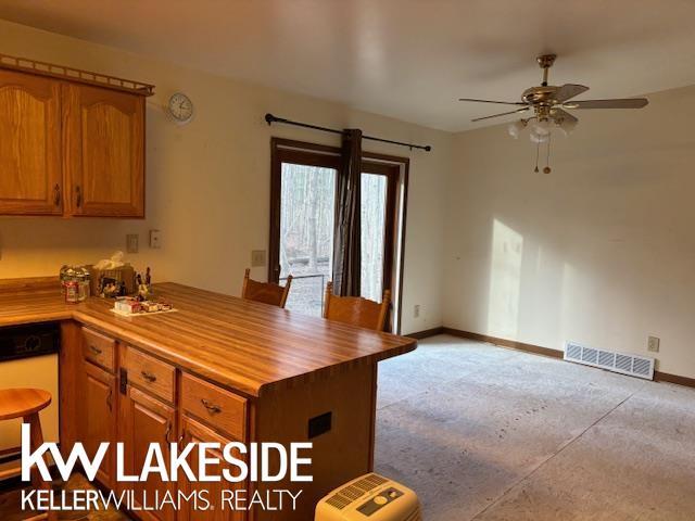 kitchen with ceiling fan, kitchen peninsula, wooden counters, and stainless steel dishwasher