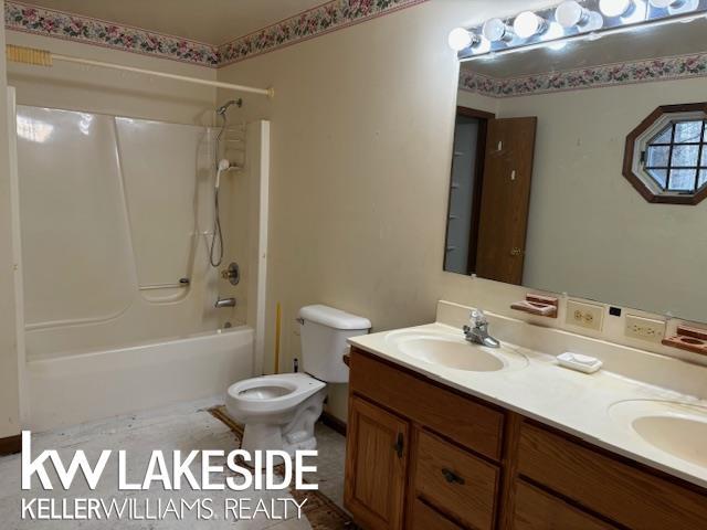 full bathroom featuring toilet, vanity, and shower / washtub combination