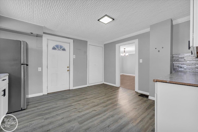 entrance foyer with crown molding, hardwood / wood-style floors, a textured ceiling, and an inviting chandelier