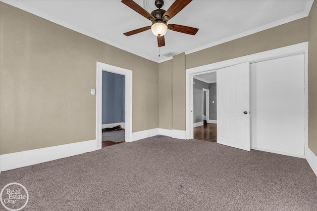 unfurnished bedroom with ceiling fan, dark carpet, ornamental molding, and a closet