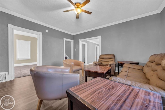 living room with a textured ceiling, light hardwood / wood-style flooring, ceiling fan, and crown molding