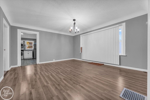 unfurnished living room featuring a textured ceiling, hardwood / wood-style flooring, and a notable chandelier