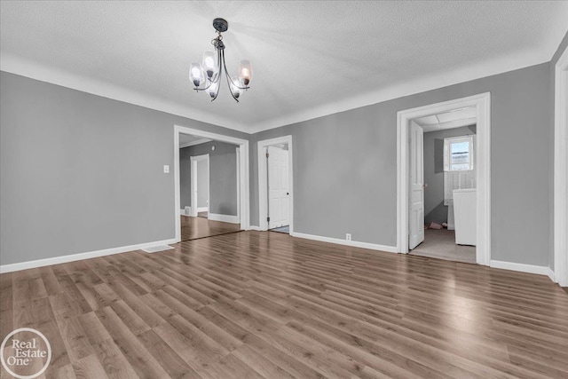 spare room with a chandelier, a textured ceiling, and hardwood / wood-style flooring