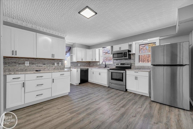 kitchen featuring white cabinetry, stainless steel appliances, a textured ceiling, and light wood-type flooring