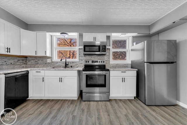 kitchen with white cabinetry, sink, light hardwood / wood-style floors, and appliances with stainless steel finishes