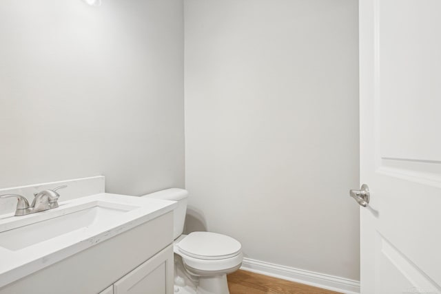 bathroom with hardwood / wood-style floors, vanity, and toilet