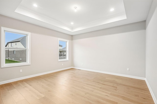 unfurnished room with light hardwood / wood-style floors and a tray ceiling