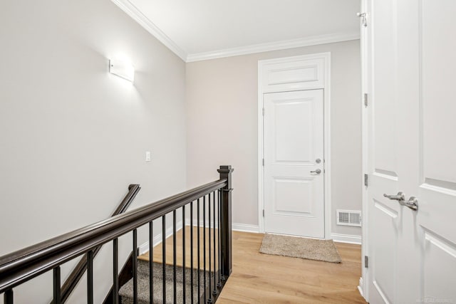 corridor with light hardwood / wood-style floors and ornamental molding