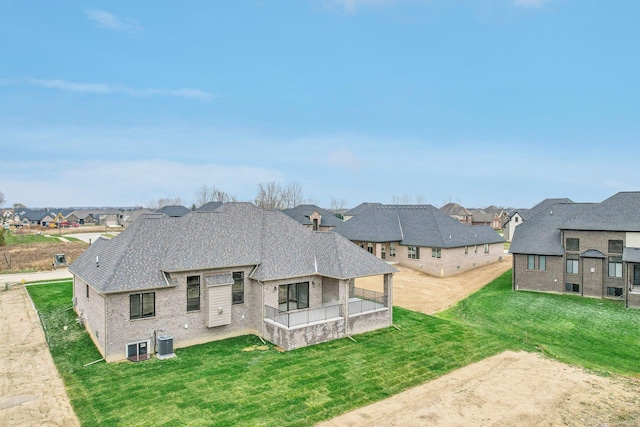 back of house with central AC unit and a yard