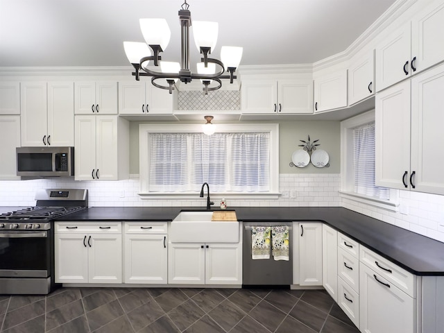 kitchen featuring decorative backsplash, stainless steel appliances, sink, pendant lighting, and white cabinetry