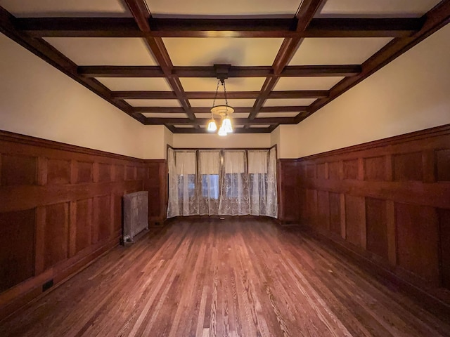 spare room with dark wood-type flooring, coffered ceiling, wooden walls, beam ceiling, and radiator heating unit