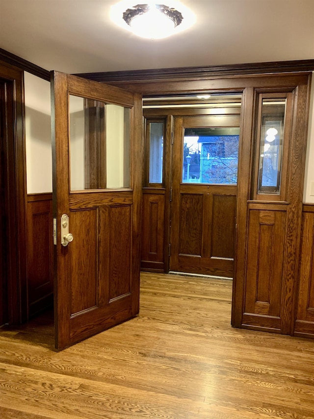 doorway to outside with wood walls and light hardwood / wood-style floors