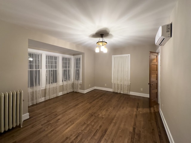 spare room with a wall mounted air conditioner, dark hardwood / wood-style floors, radiator heating unit, and a notable chandelier