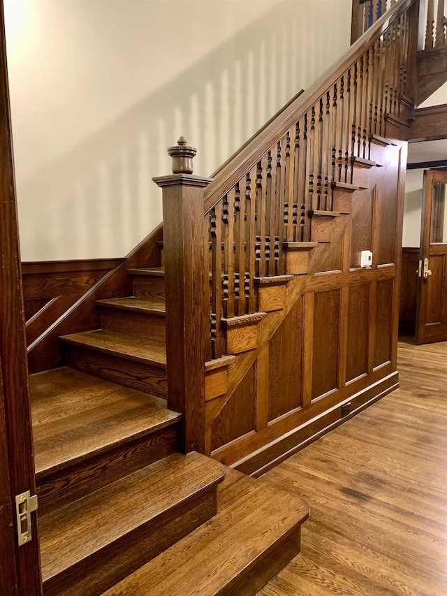 stairs featuring wood-type flooring and wooden walls