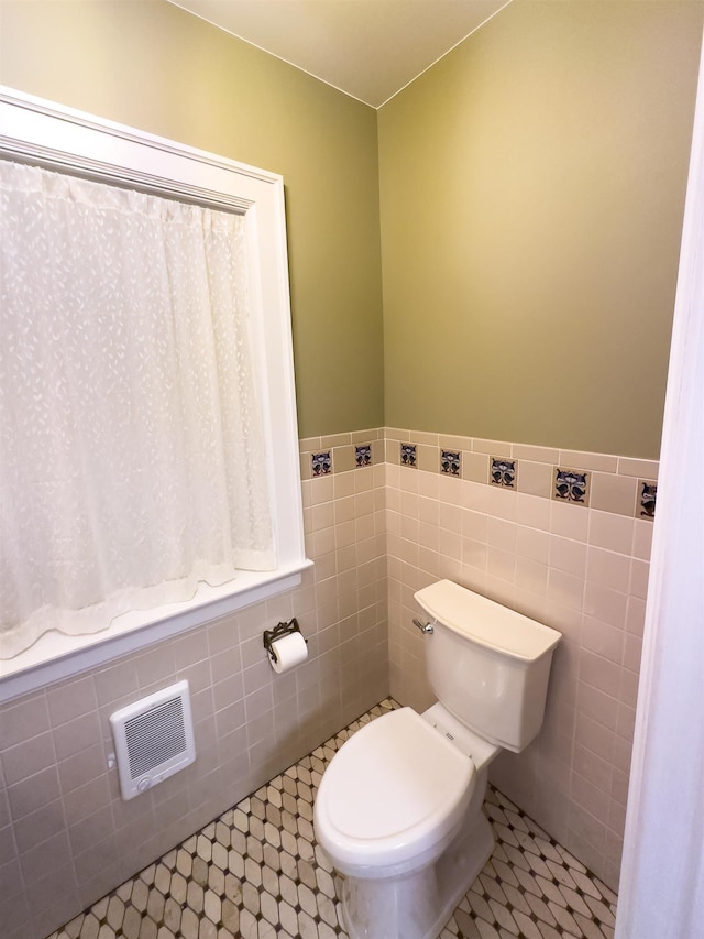 bathroom with tile patterned flooring, toilet, and tile walls