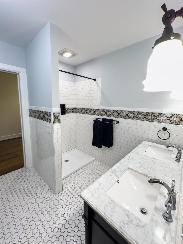 bathroom with a shower, vanity, tile walls, and tile patterned flooring