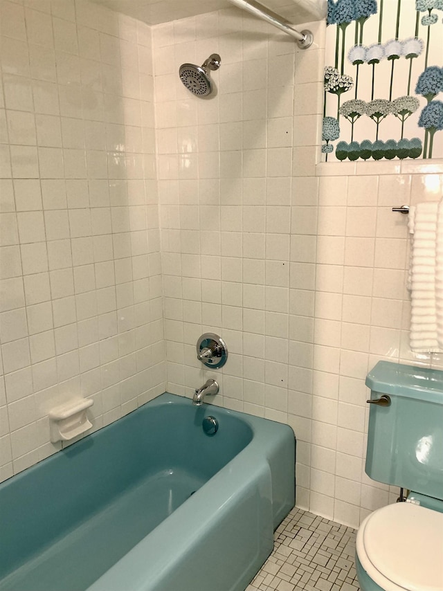 bathroom with tile patterned flooring, tiled shower / bath combo, and toilet