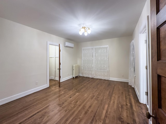 unfurnished room featuring dark hardwood / wood-style flooring, a wall unit AC, and radiator